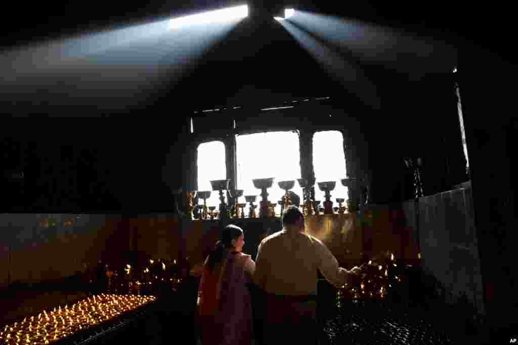 روشن کردن شمع در نیایشگاهی بودایی برای ادای احترام به کشته شدگان زلزله