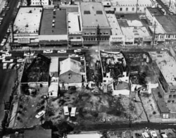 This Aug. 14, 1965 file photo shows several burned-out buildings after fires started by rioters destroyed a business block in the Watts district of Los Angeles.