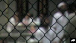 Inmates behind a fence at the military prison at Guantanamo Bay, Cuba