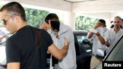 Police escort two of three British tourists suspected of stabbing an off-duty British solider to a court in Paralimni, November 5, 2012.