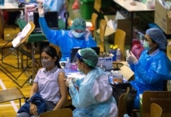 A health worker administers a dose of the Sinovac COVID-19 vaccine to a woman at Thai-Japan Bangkok Youth Center in Bangkok, Thailand, Monday, June 14, 2021. (AP Photo/Sakchai Lalit)