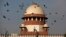 FILE - Pigeons fly past the dome of India's Supreme Court building in New Delhi, India.