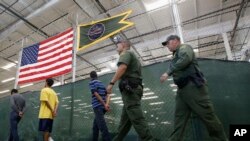 FILE - This June 18, 2014, file photo shows young detainees being escorted to an area to make phone calls as hundreds of mostly Central American immigrant children are being processed and held at the U.S. Customs and Border Protection Nogales Placement Center in Nogales, Arizona. 