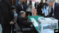 President Abdelaziz Bouteflika, sitting on a wheelchair, prepares to vote in the presidential elections in Algiers, Thursday, April 17, 2014.