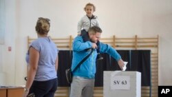 A man carrying a child on his shoulders casts his vote in a marriage referendum, in Bucharest, Romania, Oct. 6, 2018.