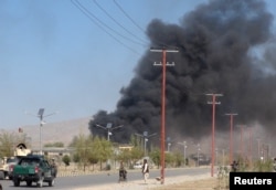 Smoke rises from police headquarters while Afghan security forces keep watch after a suicide car bomber and gunmen attacked the provincial police headquarters in Gardez, the capital of Paktia province, Afghanistan, Oct. 17, 2017.