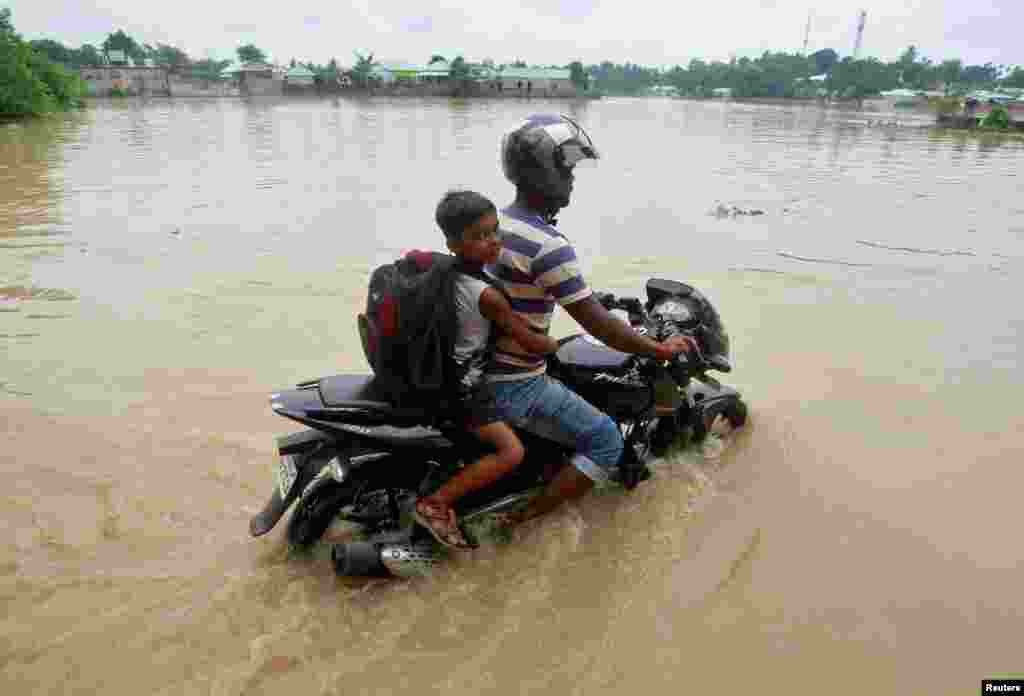 A man rides a motorcycle through a flooded road after heavy rains on the outskirts of Agartala, India.