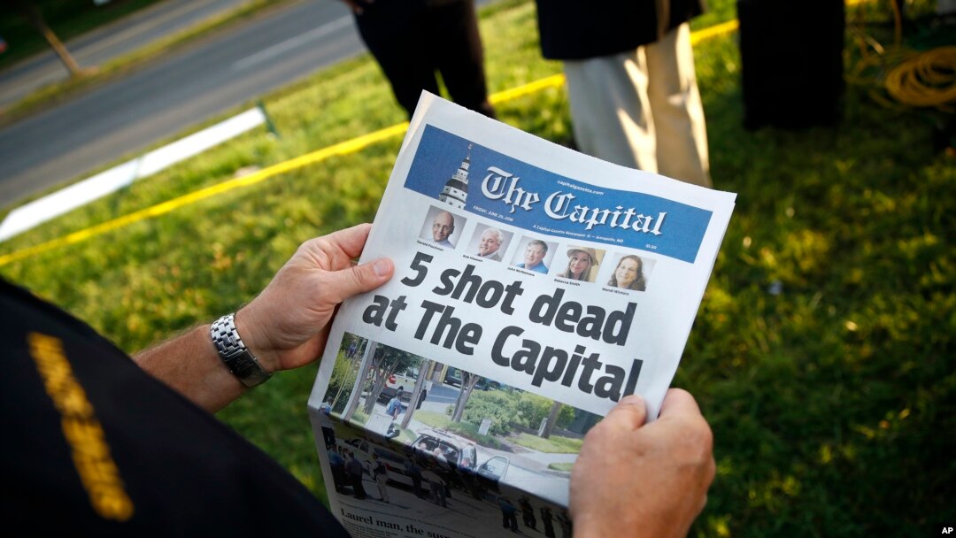Un ejecutivo del condado de Anne Arundel, en Maryland, sostiene una copia del diario The Capital Gazette cerca de las oficinas del periódico donde un hombre armado disparó y mató a cinco empleados del rotativo en Annapolis. Junio 29 de 2018.