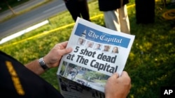 Un ejecutivo del condado de Anne Arundel, en Maryland, sostiene una copia del diario The Capital Gazette cerca de las oficinas del periódico donde un hombre armado disparó y mató a cinco empleados del rotativo en Annapolis. Junio 29 de 2018.