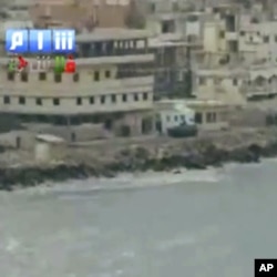 In this image taken from video made available Sunday Aug. 14, 2011, by Shaam News Network, in which they purport to show armored vehicles as they take up positions along the water front of Latakia, Syria.