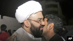 Sheik al-Nouri, in white turban, a Bahraini Shi'ite Muslim cleric who was standing trial for plotting against the regime, is kissed by a wellwisher outside the main police station in Manama, Bahrain, on being released before dawn, February 23, 2011