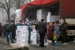 Warga berkumpul dekat sebuah trailer yang membawa bantuan makanan dan produk-produk kebersihan dari Komite Internasional Palang Merah di Kota Donetsk yang dikuasai oleh pemberontak, di Ukraina, 17 Maret 2021.