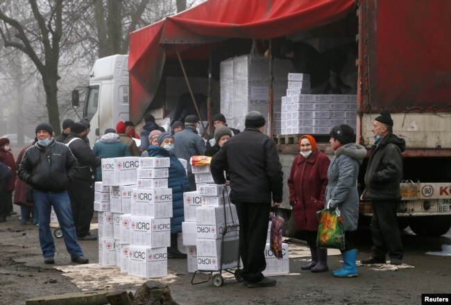 Warga berkumpul dekat sebuah trailer yang membawa bantuan makanan dan produk-produk kebersihan dari Komite Internasional Palang Merah di Kota Donetsk yang dikuasai oleh pemberontak, di Ukraina, 17 Maret 2021.