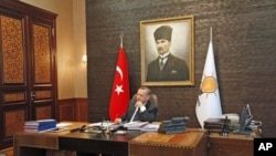 Turkey's Prime Minister Tayyip Erdogan, with a portrait of modern Turkey's founder Ataturk in the background, watches TV at his office at the AK Party headquarters in Ankara, Turkey, June 13, 2011