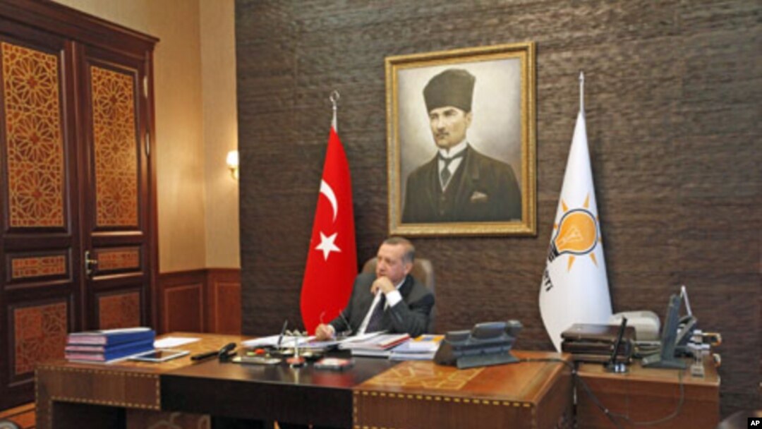 Turkey's Prime Minister Tayyip Erdogan, with a portrait of modern Turkey's founder Ataturk in the background, watches TV at his office at the AK Party headquarters in Ankara, Turkey, June 13, 2011