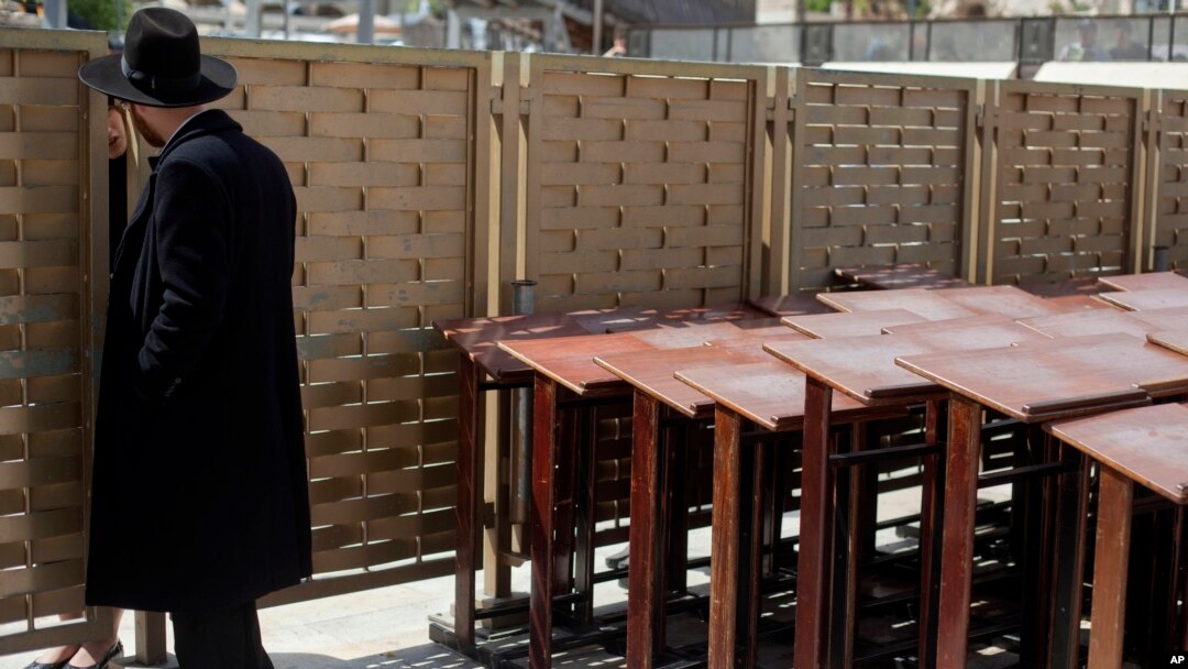An ultra-Orthodox Jewish man speaks to a woman across a fence separating men and women at the Western Wall, the holiest site where Jews can pray in Jerusalem's old city, April 10, 2013.