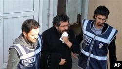 Police officers escort journalist Soner Yalcin, center, during a medical check in Istanbul, Turkey (File Photo - February 17, 2011)