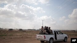 Des hommes armés du Hamas patrouillent, à bord d'un pick-up, la frontière avec Israël près de la ville de Khan Younis, dans le sud de la bande de Gaza, alors que des bulldozers militaires israéliens apparaissent en arrière-plan, 10 juin 2015.