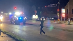 A man with a firearm raises his hands up as he walks towards vehicles during a protest following the police shooting of Jacob Blake, a Black man, in Kenosha, Wisconsin, U.S., August 25, 2020, in this still image obtained from a social media video. Brendan