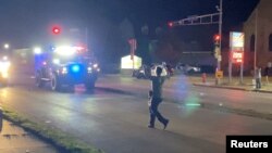 A man with a firearm raises his hands up as he walks towards vehicles during a protest following the police shooting of Jacob Blake, a Black man, in Kenosha, Wisconsin, U.S., August 25, 2020, in this still image obtained from a social media video. Brendan