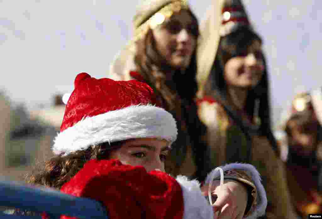 Seorang gadis kecil dari Palestina menonton parade Natal di luar Gereja Nativity di Bethlehem, Tepi Barat (24/12).ke