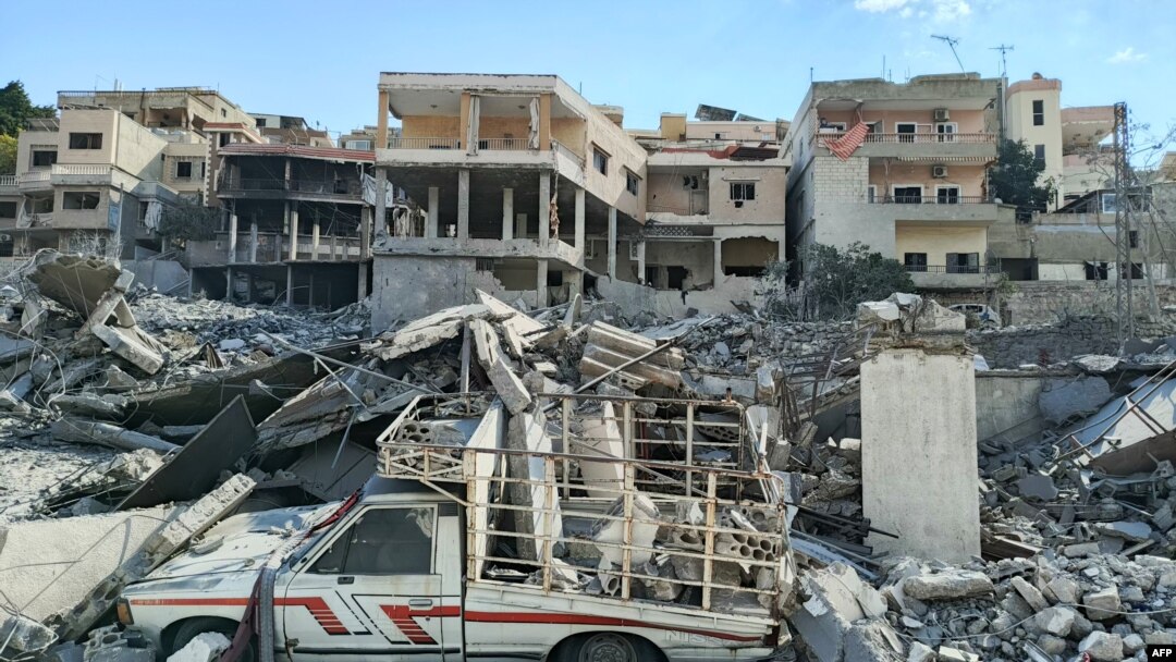 TOPSHOT - Sebuah kendaraan yang rusak tergeletak di tengah puing-puing di depan bangunan yang rusak akibat serangan udara Israel di desa Ain Baal, Lebanon selatan, di distrik Tyre, 10 November 2024.