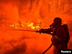 Seorang petugas pemadam kebakaran memadamkan abi di sebuah lokasi di Kharkiv, Ukraina usai serangan pesawat nirawak Rusia di tengah invasi Rusia ke Ukraina, Sabtu, 4 Mei 2024. (Foto: Vitalii Hnidyi/Reuters)