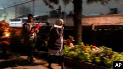 Women arrive at the cemetery to keep company with departed loved ones as they celebrate Day of the Dead at the San Gregorio Atlapulco on the outskirts of Mexico City, Nov. 1, 2024. 