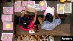 Election officials sit next to election materials to be distributed to polling stations at a distribution center, ahead of the third phase of general elections in Kochi, India, April 22, 2019. 