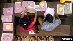 Election officials sit next to election materials to be distributed to polling stations at a distribution center, ahead of the third phase of general elections in Kochi, India, April 22, 2019. 