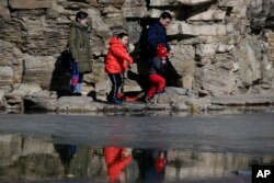 Sepasang suami-istri membawa anak-anak mereka mengunjungi taman di Beijing, 17 Februari 2019.(Foto: AP)