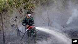 Seorang tentara menyemprotkan air untuk memadamkan api di Indralaya, Sumatra Selatan (16/9).