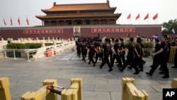 Petugas keamanan berbaris menuju jembatan di depan pintu gerbang Tiananmen, Beijing, China (31/5). Seorang pria menabrakkan mobil SUV dan membakarnya, setelah mengemudikannya melalui kerumunan turis yang ramai di tempat tersebut, tahun lalu. Dua wisatawan, pengemudi beserta istri dan ibu mertuanya dilaporkan tewas dalam insiden tersebut.
