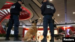 Polisi dengan anjing pelacak berjaga-jaga di dalam terminal 1 bandar udara Charles de Gaulle di Paris (19/5). (Reuters/Christian Hartmann)