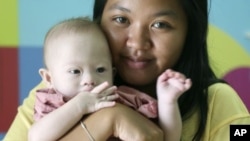 FILE - Pattaramon Chanbua, 21, poses her baby boy Gammy with Down syndrome, at a hospital in Chonburi province, southeastern Thailand, Aug. 3, 2014.