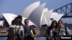 FILE - Chinese tourists taking pictures of themselves in front of the Sydney Opera House in Sydney, Australia.