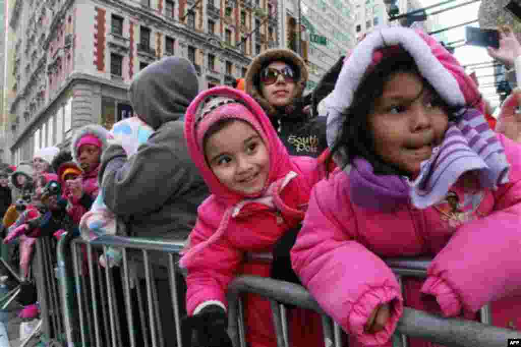 Gaila Reyes, 5, right, and her sister Michele Reyes, 4, second from right, react as they and others watch the 85th Annual Macy's Thanksgiving Day Parade as it moves across New York's 42nd Street Thursday Nov. 24, 2011. (AP Photo/Tina Fineberg)