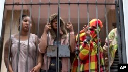 People stand behind a gate at the entrance of an abandoned residential apartment building in the middle class Flamengo neighborhood of Rio de Janeiro, April 7, 2015. 