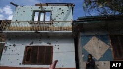 FILE - A Kashmiri girl stands in front of her damaged family house after cross-border shelling in Jura, a village of Neelum valley in Pakistan-administered Kashmir, Oct. 22, 2019.