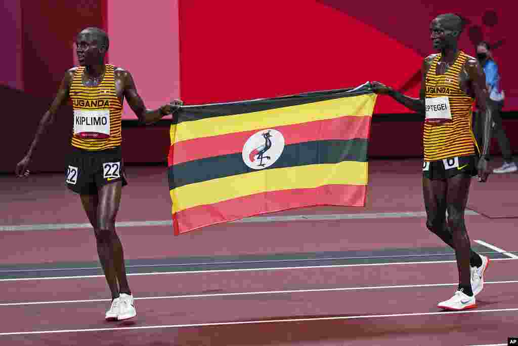 Second placed Joshua Cheptegei, left, of Uganda, and third placed teammate Jacob Kiplimo celebrate with their national flag after the runs in the men&#39;s 10,000-meters final at the 2020 Summer Olympics, Friday, July 30, 2021, in Tokyo. (AP Photo/David J. Phillip)