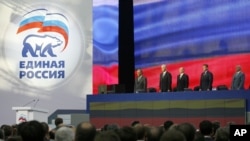 President Vladimir Putin and leading members of the United Russia party listen to the national anthem during a congress of the party in Moscow, Monday Oct. 1, 2007, with the party's logo at left. Shown from right are, Moscow Mayor Yuri Luzhkov, Emergencie