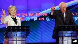 បេក្ខជន​ឈរ​ឈ្មោះ​ជា​ប្រធានាធិបតី​នៃ​​គណបក្ស​ប្រជាធិបតេយ្យ សមាជិក​ព្រឹទ្ធសភា​លោក Bernie Sanders នៃ​រដ្ឋ​ Vermont (ស្តាំ) និង​លោក​ស្រី ​Hillary Clinton ជជែក​គ្នា​ក្នុង​ការ​ជជែក​ដេញដោល​បឋម​រវាង​បេក្ខជន​ឈរ​ឈ្មោះ​ជា​ប្រធានាធិបតី ដែល​ធ្វើ​ឡើង​ដោយ​ទូរទស្សន៍ CNN នៅ Brooklyn Navy Yard ក្រុង​ ញូយ៉ក ថ្ងៃ​ព្រហស្បតិ៍ ទី​១៤ ខែ​មេសា ឆ្នាំ​២០១៦។ (AP Photo/Seth Wenig)