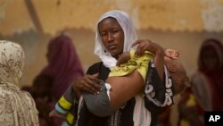 Une femme porte son enfant pour une consultation dans un centre de nutrition à Mao, dans la région du Kanem, Tchad, 17 avril 2012. 