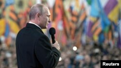 FILE - Russian President Vladimir Putin addresses the audience during an event marking the first anniversary of the Crimean treaty signing, with St. Basil's Cathedral seen in the background, in Moscow, March 18, 2015. 