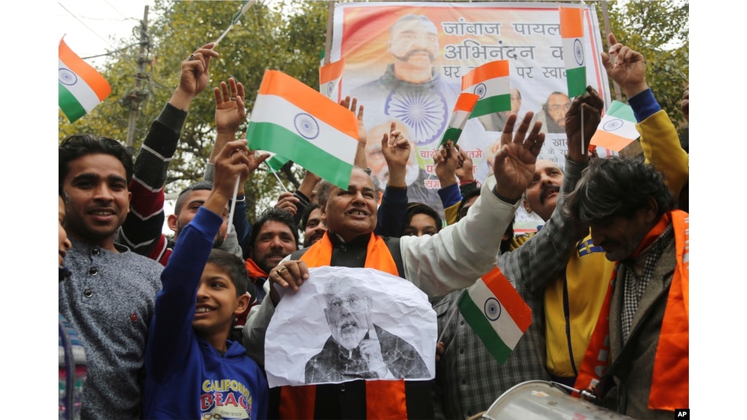 Indians wave national flags as they wait for the release of an Indian air force pilot by Pakistani authorities, in Jammu, India, March 1, 2019.