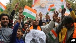 Indians wave national flags as they wait for the release of an Indian air force pilot by Pakistani authorities, in Jammu, India, March 1, 2019.