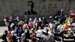 Opposition supporters sit next to a graffiti of 17-year-old protester Neomar Lander, who died during clashes with security forces, as they attend a rally against Venezuelan President Nicolas Maduro's government in Caracas, Venezuela, June 9, 2017. 