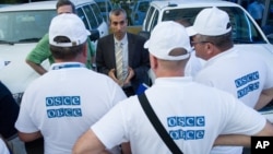 FILE - The head of the OSCE (Organization for Security and Cooperation in Europe) mission, acting Chief Observer Paul Picard, center, speaks to the other members at a hotel in Rostov-on-Don, Russia, July 29, 2014. 