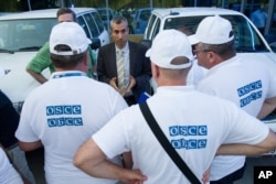 FILE - The head of the OSCE (Organization for Security and Cooperation in Europe) mission, acting Chief Observer Paul Picard, center, speaks to the other members in Rostov-on-Don, Russia, July 29, 2014. OSCE observers will be participating in the U.S. election.
