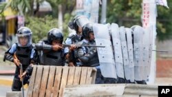A Nicaraguan police officer aims his weapon at protesting students during a third day of violent clashes in Managua, Nicaragua, April 20, 2018. The Organization of American States have expressed concern over the heavy-handed crackdown, while also calling 